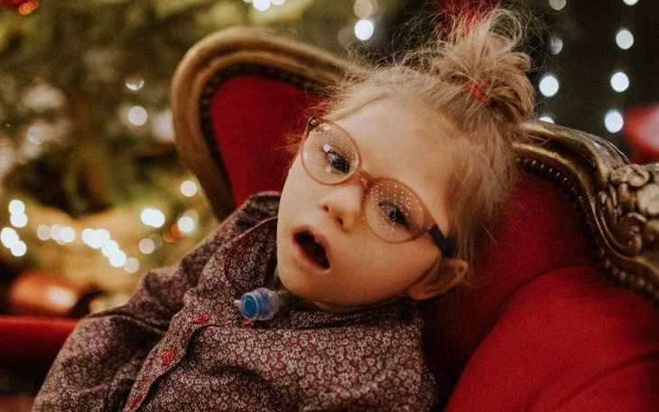 Dziewczynka w okularach, siedząca na czerwonym fotelu.