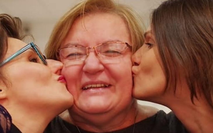 Trzy kobiety, uśmiechające się i całujące się w policzki.