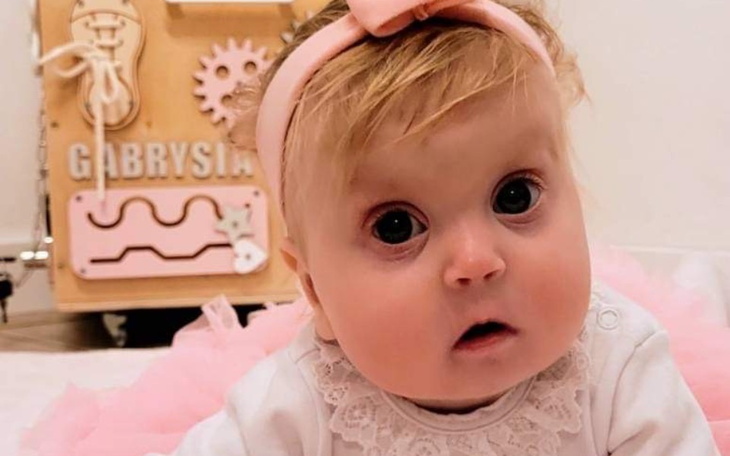 Mała dziewczynka w różowej sukience, patrzy z ciekawością.