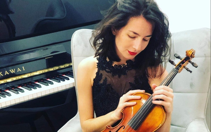 Młoda kobieta grająca na skrzypcach w eleganckim stroju.