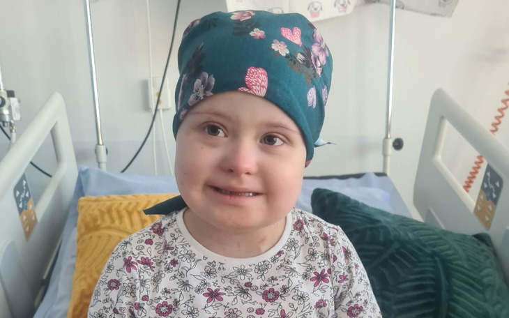 Dziewczynka w szpitalu, uśmiechająca się w kolorowej chustce.