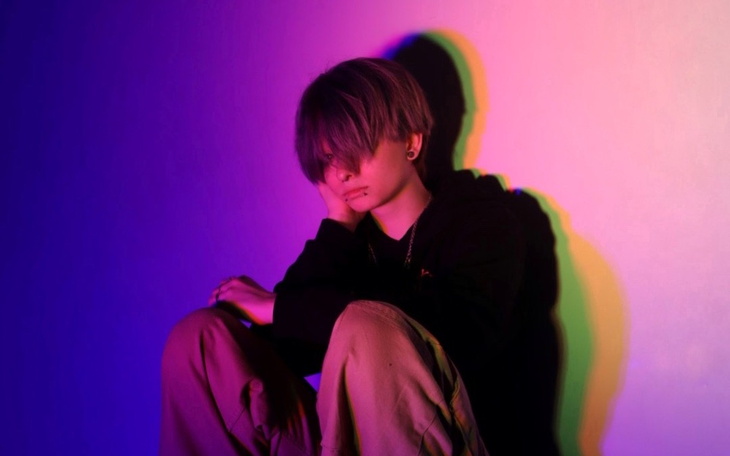 Młody człowiek w kolorowym świetle, zamyślony.