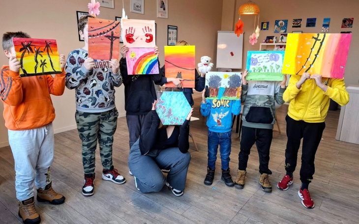 Dzieci trzymające swoje prace plastyczne, uśmiechnięte.