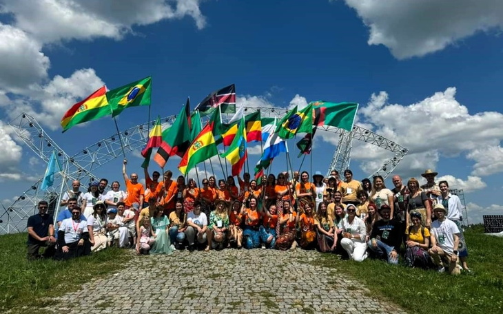 Grupa ludzi z flagami różnych krajów na tle nieba.