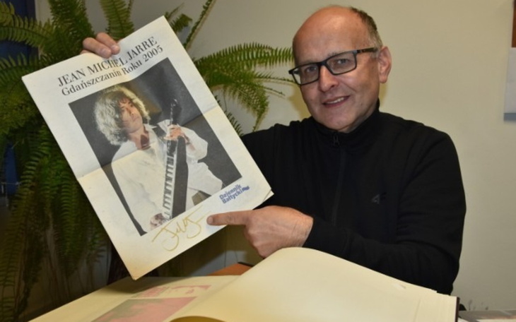 Mężczyzna trzyma plakat Jean-Michel Jarre'a z autografem.