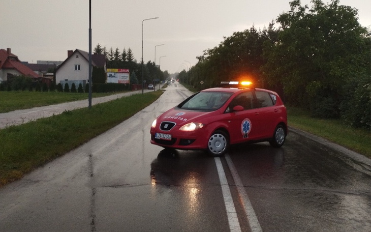 Czerwony samochód ratunkowy blokujący drogę w deszczową pogodę.
