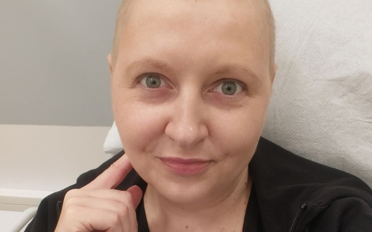 Kobieta z krótkimi włosami uśmiecha się do kamery.