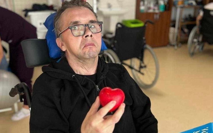 Mężczyzna w wózku inwalidzkim trzyma czerwone serce.