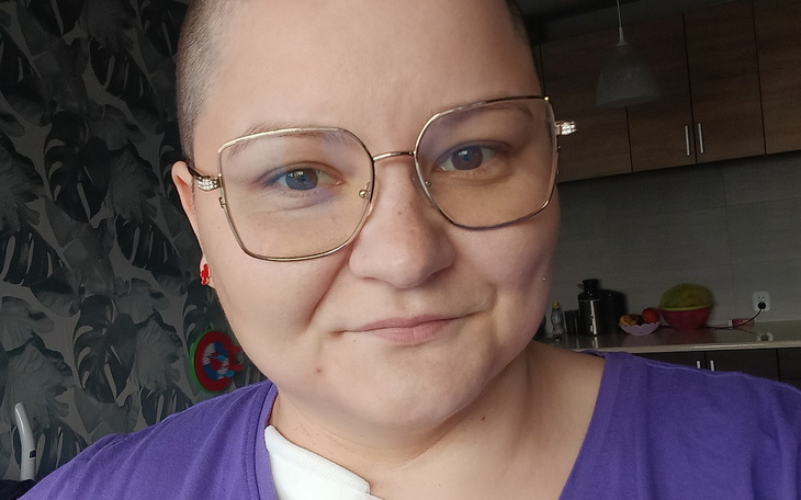 Kobieta z okularami i krótkimi włosami, uśmiechająca się do kamery.