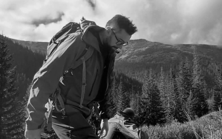 Mężczyzna w górach, ubrany w odzież turystyczną, w otoczeniu natury.