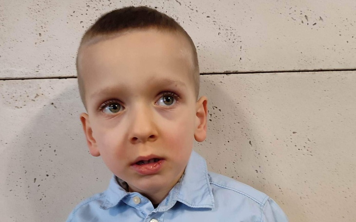 Mały chłopiec z zaniepokojonym wyrazem twarzy, patrzący w dal.