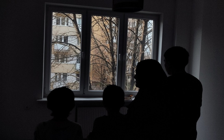 Cztery sylwetki ludzi przy oknie, patrzących na zewnątrz.