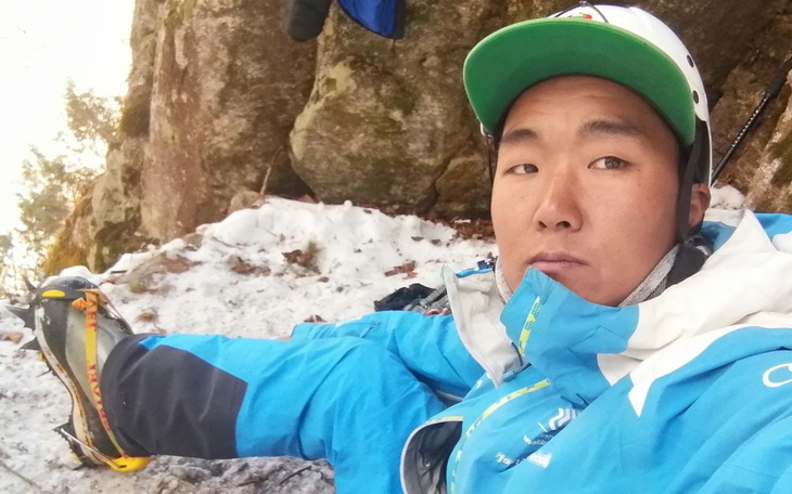 Osoba w niebieskiej kurtce na śniegu, przygotowująca się do wspinaczki.