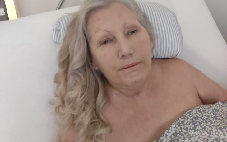 Starsza kobieta leżąca w łóżku, z delikatnym uśmiechem.