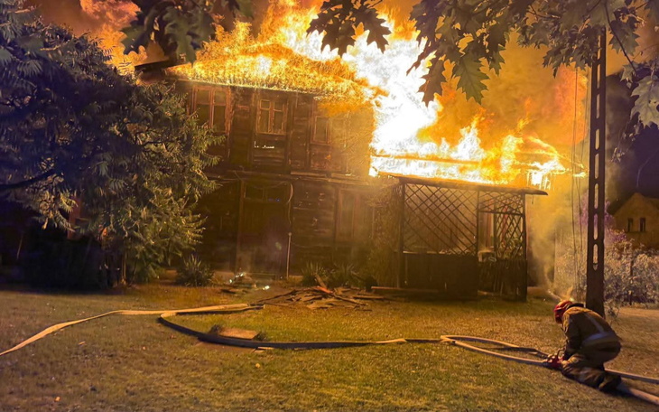 Płonący dom, strażak pracuje nad ugaszeniem ognia.
