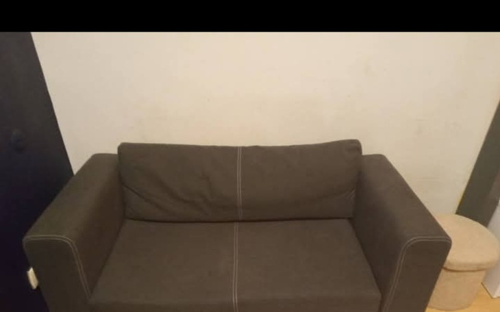 Sofa w kolorze szarym, umieszczona na tle białej ściany.