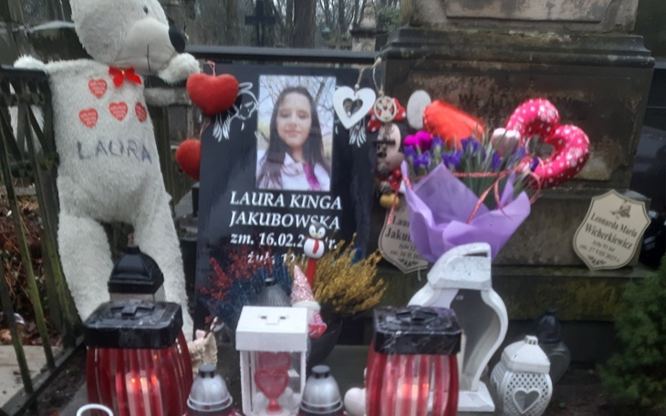 Miejsce pamięci z portretem i kwiatami na grobie.