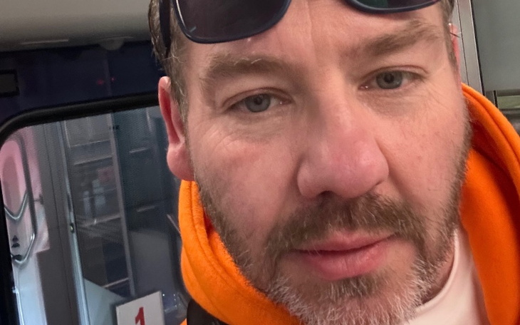 Mężczyzna w pomarańczowej bluzie, selfie w autobusie.