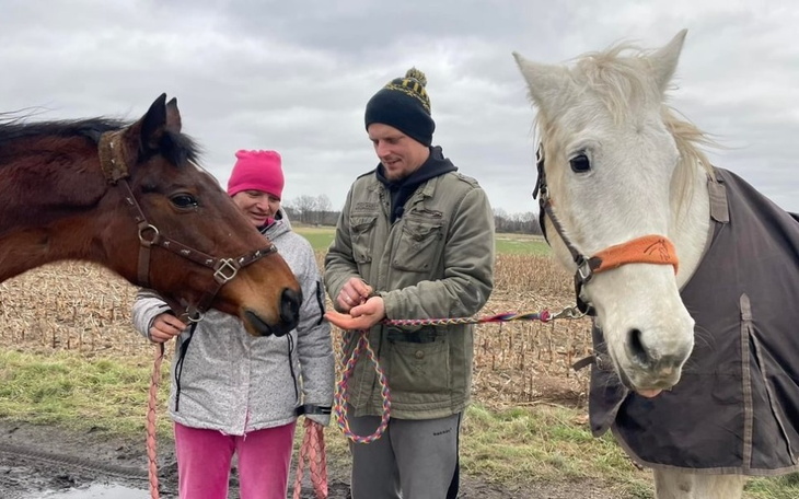 Osoba z końmi na tle pola, w zimowej scenerii.
