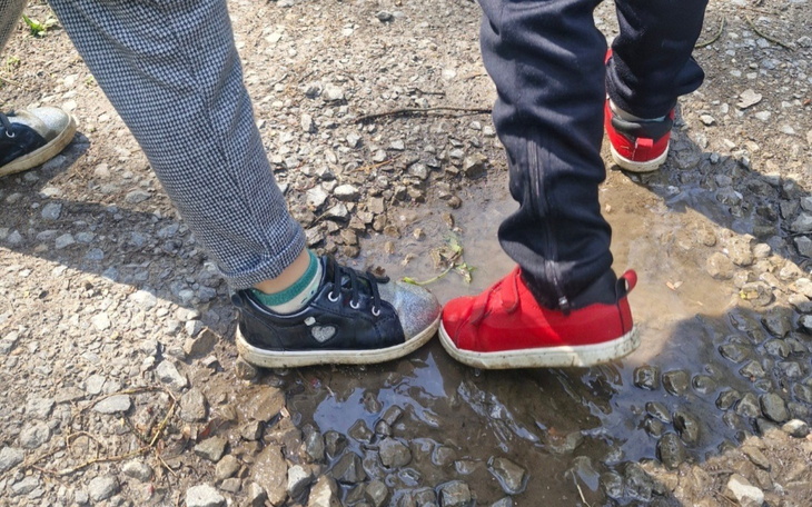 Dziecięce buty w kałuży na kamienistej drodze.