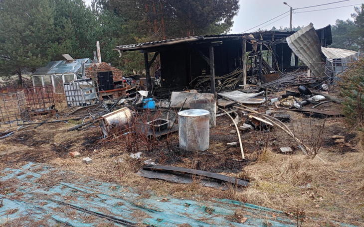 Zniszczony budynek z resztkami po pożarze w otoczeniu przyrody.