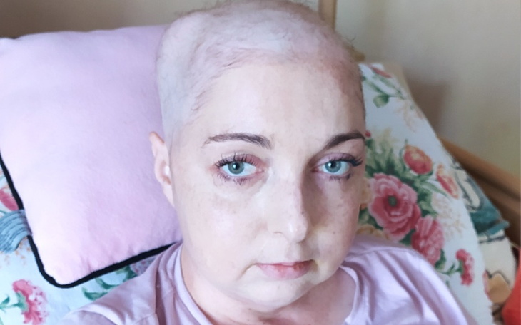 Kobieta z krótkimi włosami, leżąca na poduszce w domu.