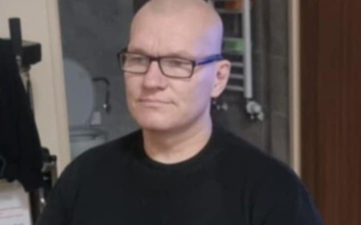 Mężczyzna w czarnej koszulce, z okularami, w zamyśleniu.