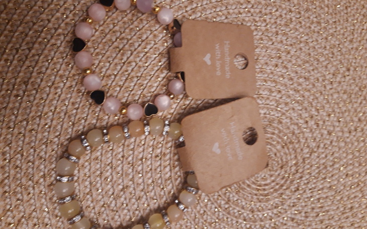 Trzy bransoletki na tle plecionki, w różnych kolorach.