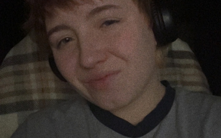 Osoba w słuchawkach uśmiecha się do kamery.