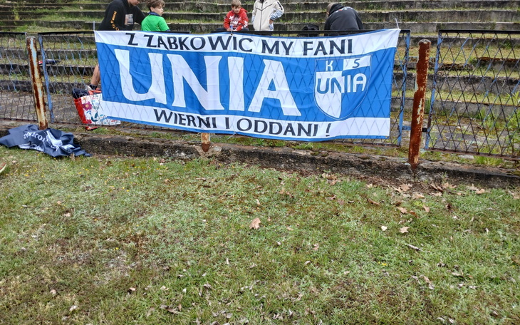 Baner kibiców z napisem 'UNIA' na stadionie.