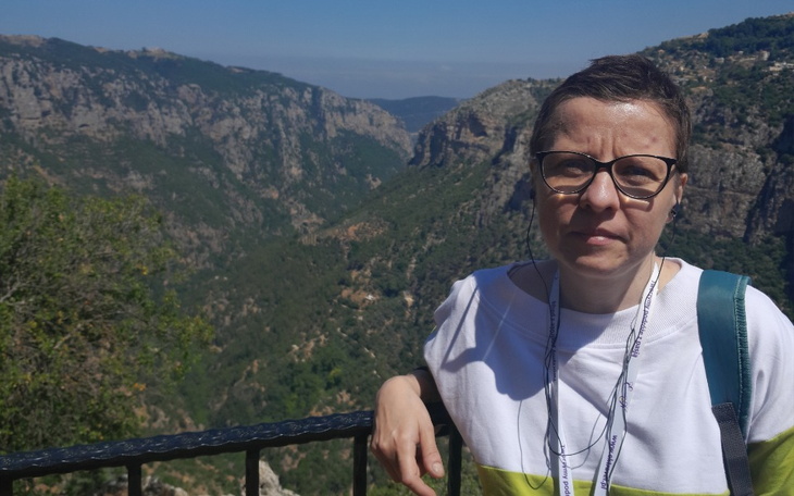 Kobieta na tle gór, z poważnym wyrazem twarzy.