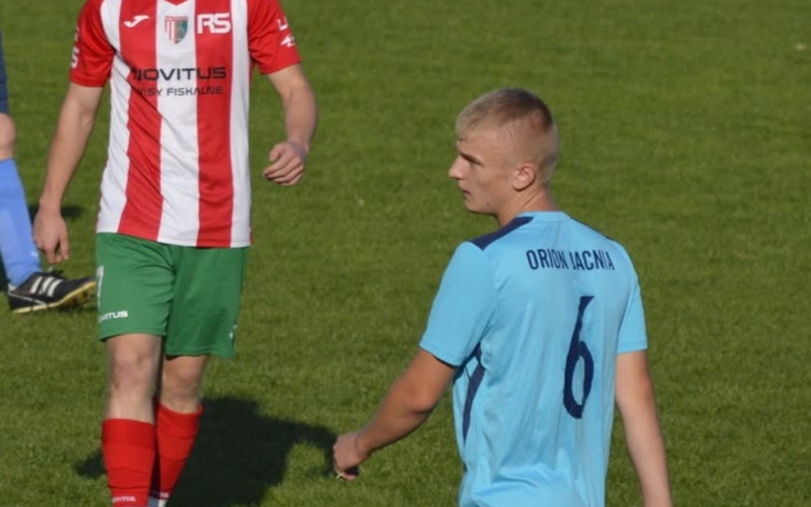 Młody piłkarz na boisku, w niebieskiej koszulce.