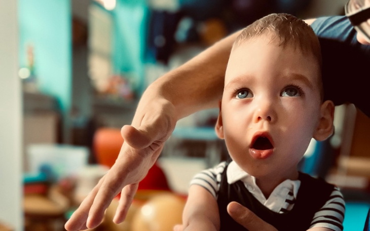 Mały chłopiec z otwartymi ustami, wyciągający rękę w stronę obiektu.