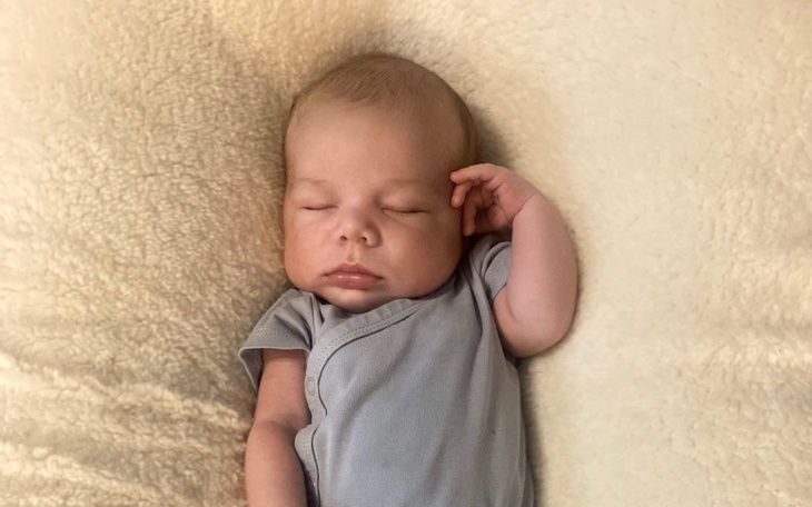 Noworodek śpiący na jasnym kocyku.