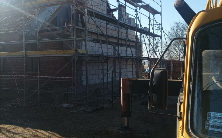 Budowa domu z rusztowaniami i maszynami budowlanymi.