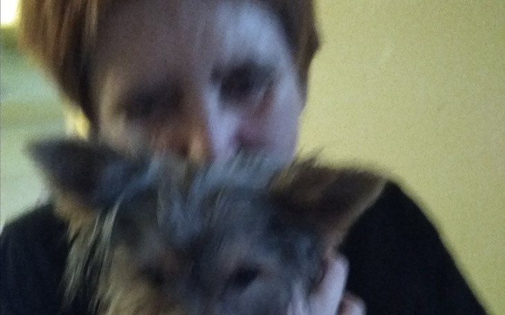 Rozmyte zdjęcie kobiety trzymającej małego psa.