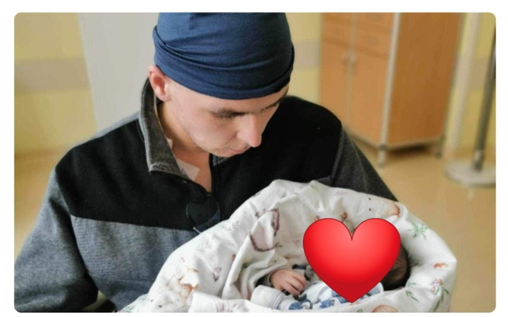 Mężczyzna trzymający noworodka w szpitalu.