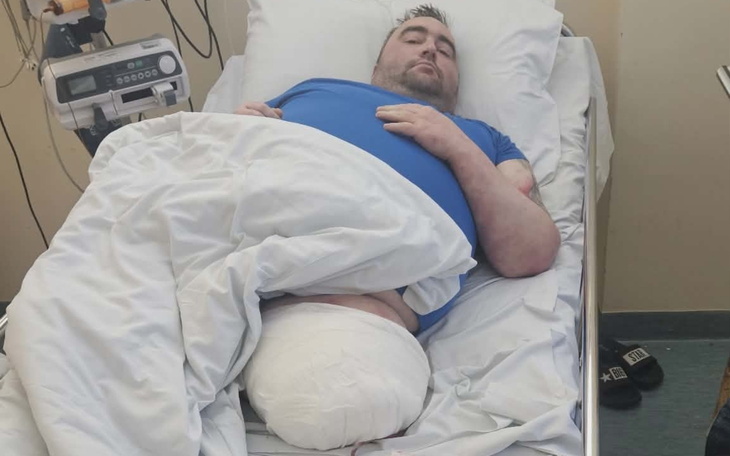 Mężczyzna leżący w szpitalnym łóżku po operacji.