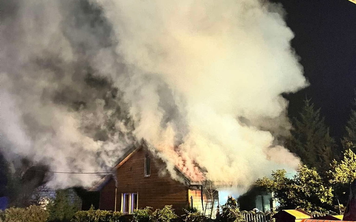 Dom w ogniu, z dużą ilością dymu unoszącego się w powietrzu.