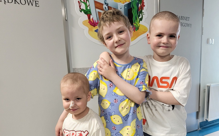 Trójka dzieci w szpitalu, uśmiechnięte i radosne.
