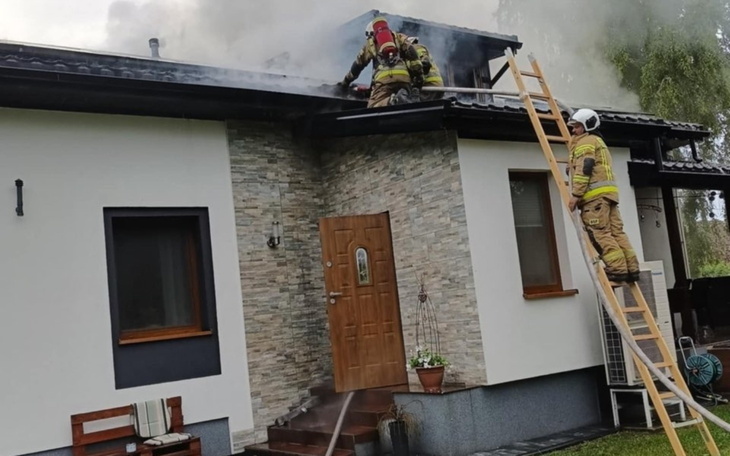 Strażacy gaszący pożar na dachu domu.