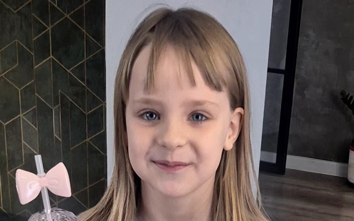 Uśmiechnięta dziewczynka trzymająca napój w różowym kubku.