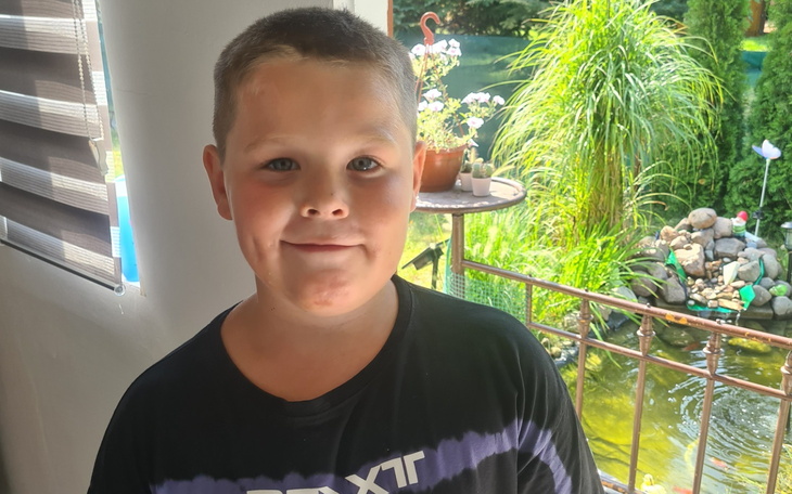 Chłopiec uśmiechający się w pobliżu ogrodu.