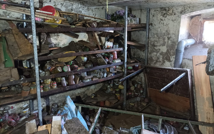 Zabałaganione pomieszczenie z półkami pełnymi słoików.