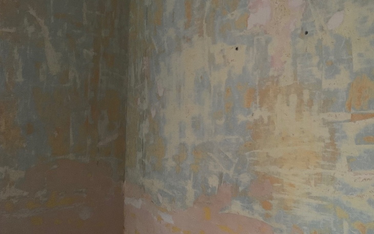 Ściana z odrapaną farbą, w tle widoczne plamy.