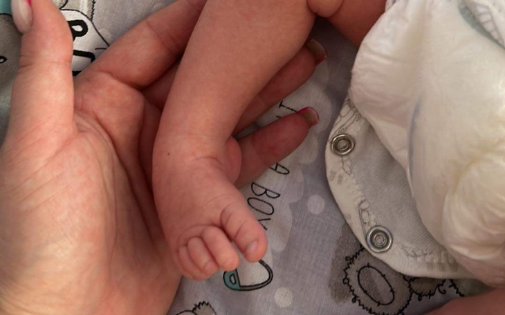 Dłoń dorosłego trzymająca małą rączkę dziecka.