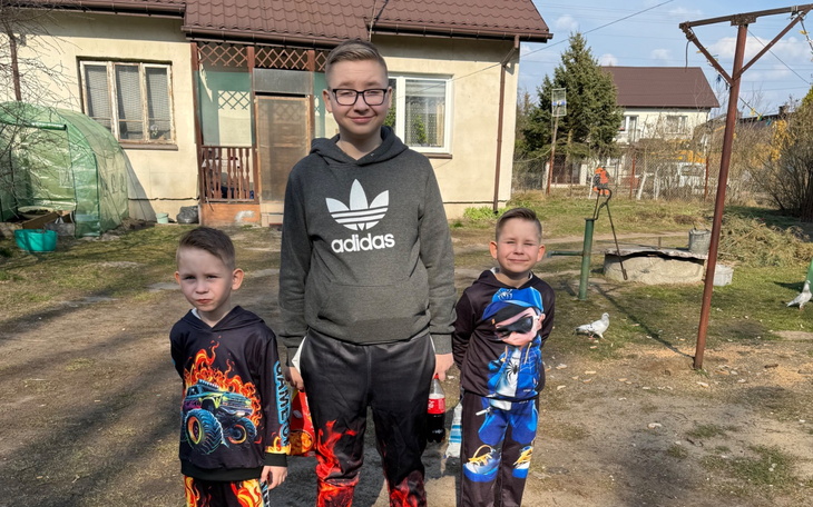 Trzech chłopców na podwórku, uśmiechnięci.