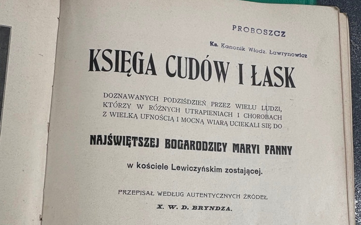 Stare tomy i dokumenty leżące na kartce z napisem KSIEGA CUDÓW I LASK.