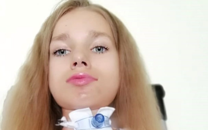 Młoda dziewczyna z tracheostomią, patrząca w obiektyw.