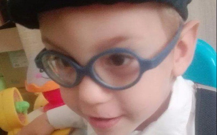 Chłopiec w okularach, uśmiechający się do kamery.